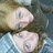 Pixelated image of two light pink heart shapes with blue eyes, positioned vertically against a blurred background of brown and blue tones.