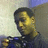 Pixelated static image of a person with dark hair and yellow-toned skin wearing a dark blue top against a light background.