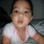 Pixelated image of a child in a white shirt with pink trim, mouth open as if speaking or crying against dark background.