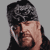 Pixelated static image of a person with dark hair covering their face, wearing a black top against a gray background.