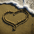 A beach scene with a heart drawn in sand and text reading 'Sorry, dude. I like blondes. :]'.