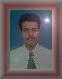 A static portrait of a person in a white shirt and dark patterned tie against a blue background, framed with red and white borders.