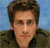 Pixelated portrait of a person with short brown hair wearing a dark jacket against a blue background.