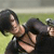 Two figures in dark clothing embrace on a grassy field with a blurred background.