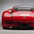 Red vehicle with white accents and dark wheels, viewed from a low angle against a light gray background.