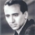 Pixelated grayscale portrait of a person with dark hair styled upward, wearing a dark jacket over a light collared shirt against a gradient background.