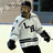 Pixelated image of a person in a white hockey jersey with dark accents, black gloves, and dark pants, standing on an ice rink with a blurred background.