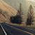 Pixelated static image of a dark vehicle on a road with two tall structures in the background under a hazy sky.