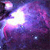 A static pixelated image of a nebula with swirling purple and pink hues against a dark background, featuring bright white and light blue star-like points.