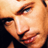 Pixelated close-up of a person's face showing eyes, nose, and mouth with warm skin tones against dark background.