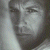 A grayscale pixelated portrait of a person with short hair against a light background, adjacent to green text on dark green.