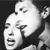 Two pixelated faces in profile view, one behind the other, with visible eyes, noses, and mouths against a dark background.