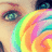 A pixelated close-up of a person's face with rainbow-colored hair, showing one eye and part of the nose against a light background.