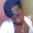 Pixelated static image of a person with dark hair wearing a blue cap and white shirt, set against light brown background.