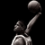 Pixelated grayscale image of a figure holding a large spherical object above its head against black background.