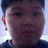 Pixelated close-up of a person's face with dark hair, visible ear, and light background.