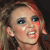 A pixelated close-up of a person with light skin, blue eyes, and reddish-brown hair, mouth open in a shout or yell.