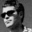 Black-and-white pixelated static icon of a person's face with short dark hair, wearing sunglasses and a headband, smiling slightly against a gray background.