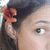 A person with dark hair and a red flower accessory in their hair, showing eye and ear details across three views.
