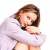 A pixelated image of a person in white clothing holding their knees, next to green text on dark background.