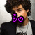 A person with curly brown hair wears a black jacket over a white shirt, shown in three where text overlays change from 'So' to 'Cute!' while the lower remains static