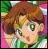 Pixelated image of a person with light brown hair and green eyes, wearing a green top against a multicolored background.