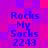 Pixelated text 'Rocks My Socks 2243' in blue on a purple-pink gradient background with four identical copies arranged in a