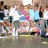 Pixelated static image of multiple figures in a group pose with varied clothing colors including white, blue, pink, and brown.