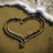 A heart drawn in sand with a wave approaching, showing subtle animation changes across frames.
