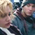 Two figures in close proximity with one figure's hand near the other's face, rendered in low-resolution pixelated style with muted tones.