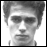 Static grayscale pixelated image of a person's face with short hair, visible eyes, nose, mouth, and part of the neck against a white background.