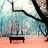 Pixelated static image shows a black bench on a peach-colored ground beneath a large black tree branch against a blue and white sky.
