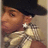 Pixelated image of a person wearing a dark cap and light-colored shirt with a patterned design, viewed from the side.