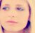 Pixelated close-up of a person's face with light skin tone, blue eyes, and purple hair strands visible on the left side.