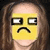 A static image of a person with long brown hair wearing a yellow emoji mask showing a sad expression with downturned mouth and squinted eyes.