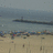 Pixelated beach scene with dark horizontal structure above sandy foreground and scattered colored pixels in midground.
