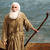A pixelated figure with white hair and beard wears a long brown robe and holds a dark curved staff against a blue-gray background.