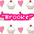 Pixelated image with repeating cupcake and heart motifs, pink text reading "Brooke" in quotes, purple emoticon sequence on white background.