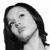 Black-and-white pixelated image of a person with long dark hair, closed eyes, and a neutral expression, cropped to show head and shoulders against a plain background.