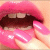 A close-up of pink lips with a tongue extended, showing teeth and dark brown lip color against light skin.