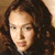 Pixelated static image of a person with long dark hair and light skin, cropped to show head and shoulders against a brown background.