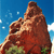 Pixelated brown bear head against blue sky with white clouds, green foliage at base, static image with no visible text or motion.