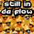 Pixelated image with bold text "still in da flow" over a background of repeated cartoon faces with red cheeks and blue accents.