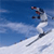 Pixelated static image of a skier in mid-air against a blue sky and snowy slope background.