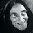 Pixelated grayscale image of a person's face with dark hair against a black background, showing neutral expression and visible eyes nose mouth.
