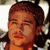 Static pixelated image of a person's face with brown hair and orange-toned skin, wearing an orange top against a blurred background.