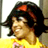 Pixelated static image of a character with dark hair and red headband wearing yellow top, cropped to show upper body against light background.