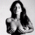 Pixelated grayscale image of a person with long dark hair, bare shoulders, and visible chest area against light background.