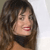 A pixelated close-up of a person with long brown hair, red lips, and a black choker against a light background.