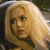Pixelated close-up of a person with light-colored hair, wearing a dark top against a blurred background.